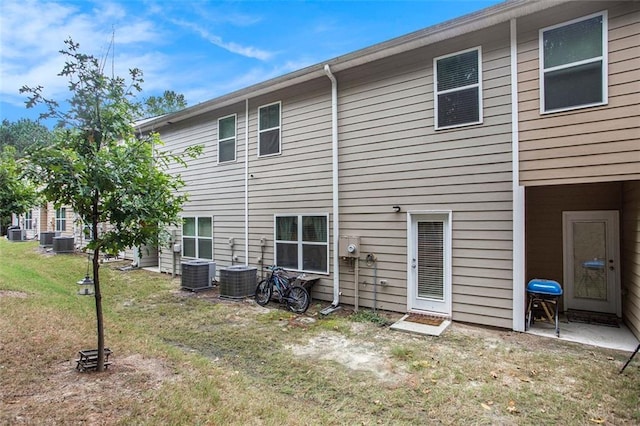 back of house with central air condition unit and a yard