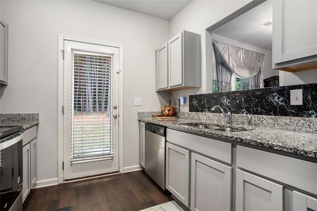 kitchen with dark hardwood / wood-style floors, light stone countertops, sink, and stainless steel appliances