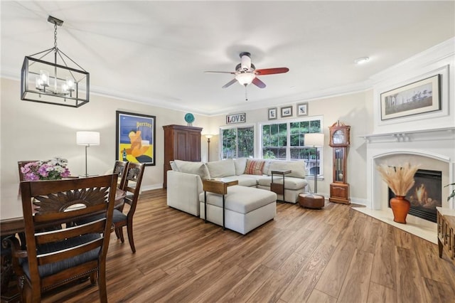 living room featuring hardwood / wood-style floors, ceiling fan with notable chandelier, and ornamental molding