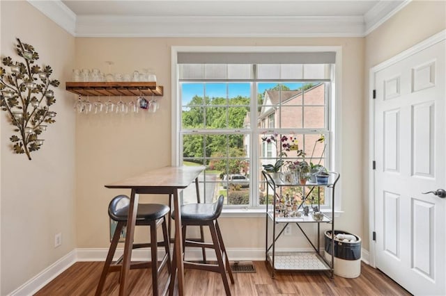 dining area with wood-type flooring, bar, and ornamental molding