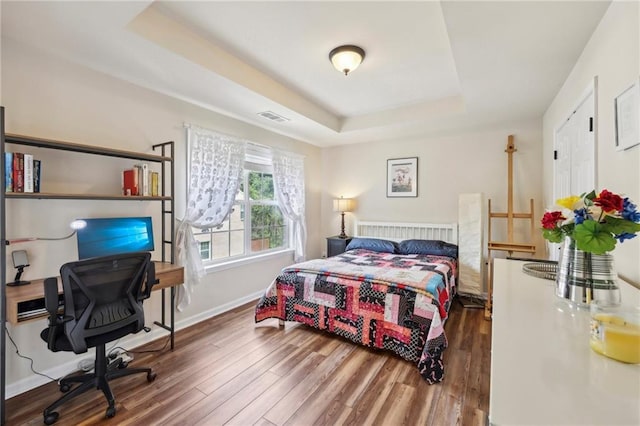 bedroom featuring dark hardwood / wood-style flooring and a raised ceiling