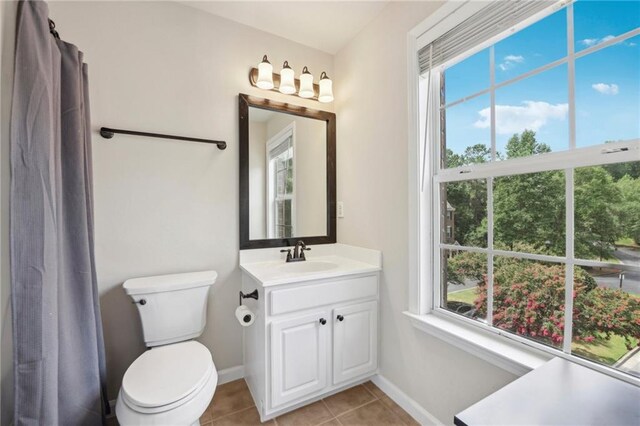 bathroom with toilet, plenty of natural light, vanity, and tile patterned floors