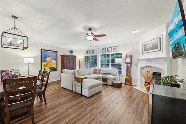 living room featuring ornamental molding, ceiling fan with notable chandelier, and dark hardwood / wood-style floors