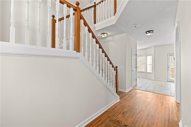 stairs with wood-type flooring and a textured ceiling