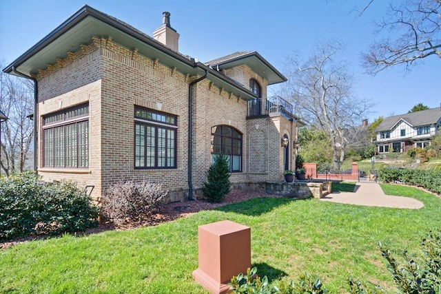 view of side of home featuring a lawn and a balcony