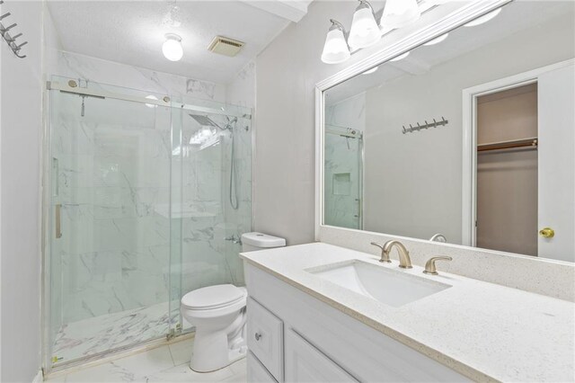 bathroom with a shower with door, vanity, and toilet