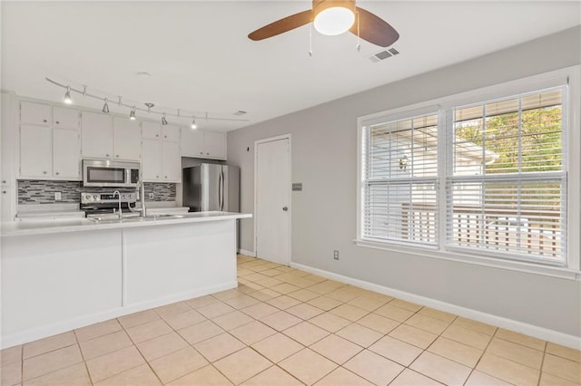 kitchen featuring backsplash, white cabinetry, light tile patterned floors, and stainless steel appliances