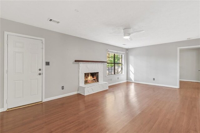 unfurnished living room with hardwood / wood-style floors, ceiling fan, and a high end fireplace