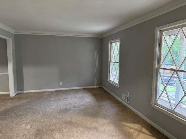 carpeted spare room featuring baseboards, visible vents, and ornamental molding