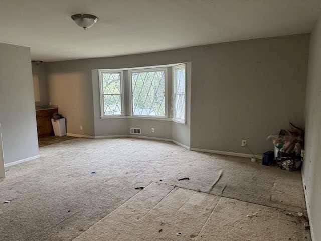 unfurnished living room featuring baseboards and visible vents