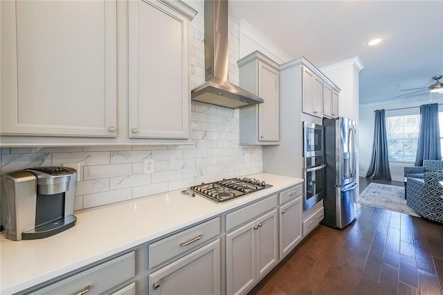 kitchen featuring stainless steel appliances, dark wood-style flooring, light countertops, decorative backsplash, and wall chimney exhaust hood