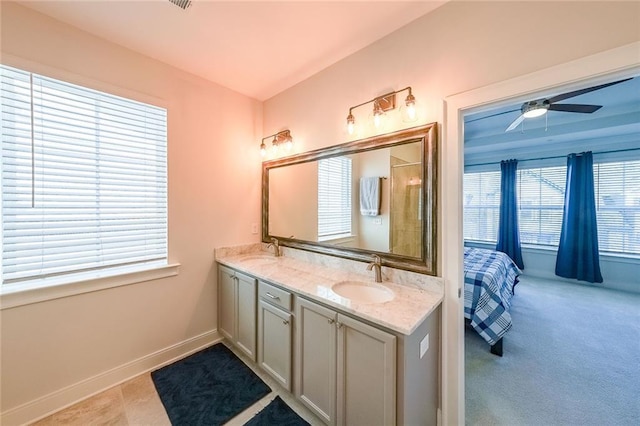 ensuite bathroom with a shower with door, a sink, baseboards, and double vanity