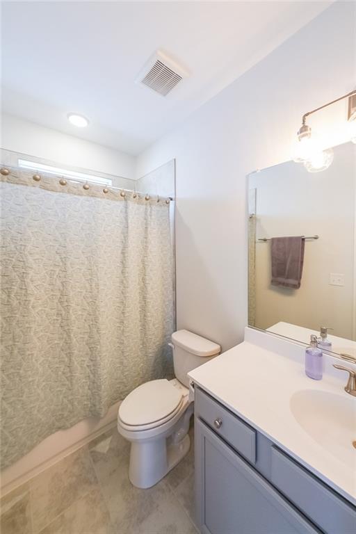 bathroom featuring visible vents, vanity, toilet, and tile patterned floors