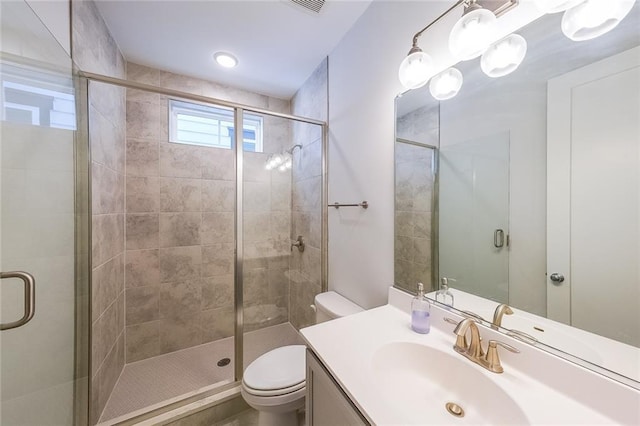 bathroom with toilet, a stall shower, and vanity