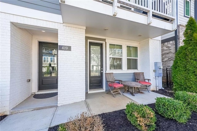 doorway to property featuring a porch and brick siding