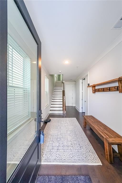 interior space with stairs, visible vents, wood finished floors, and ornamental molding