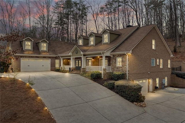 new england style home with a porch, brick siding, and driveway