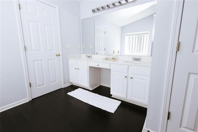 bathroom featuring wood-type flooring, vanity, and vaulted ceiling