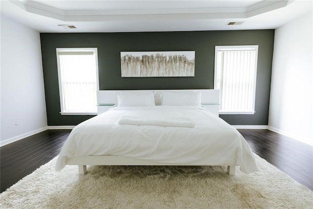 bedroom with a raised ceiling, crown molding, and dark hardwood / wood-style flooring