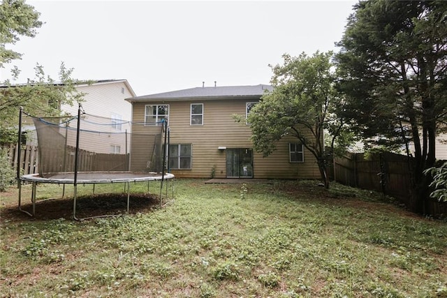 rear view of house featuring a yard and a trampoline