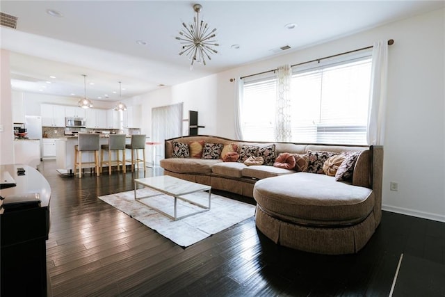 living room with dark wood-type flooring and an inviting chandelier