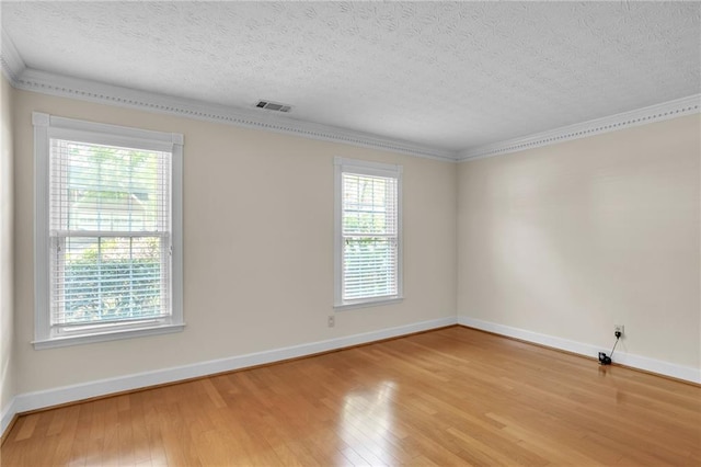 unfurnished room featuring light wood-type flooring, healthy amount of natural light, baseboards, a textured ceiling, and crown molding