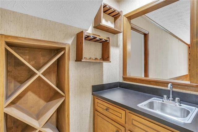 wine cellar featuring a sink, a textured ceiling, wallpapered walls, and crown molding