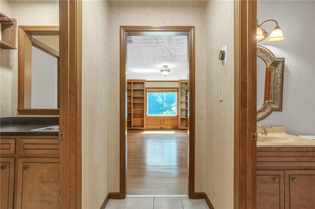 corridor with a sink and light tile patterned flooring