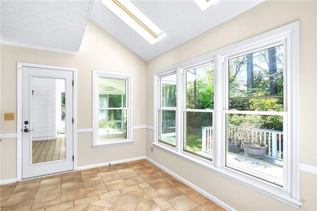 entryway with a skylight, plenty of natural light, vaulted ceiling, light tile patterned flooring, and baseboards