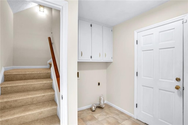 laundry area featuring electric dryer hookup, cabinet space, and baseboards