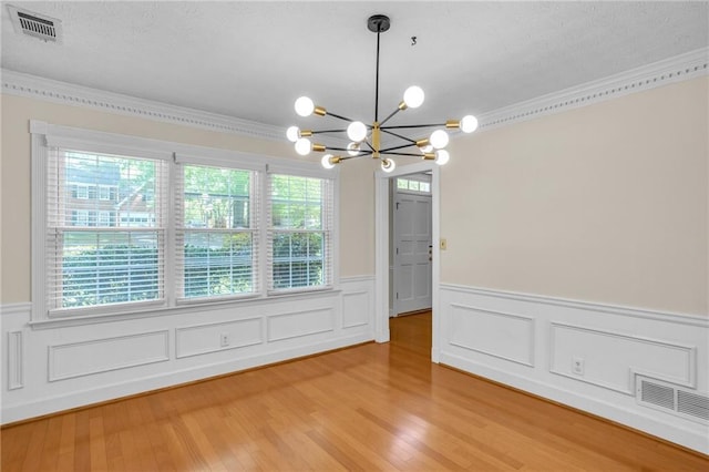 unfurnished room with a wainscoted wall, a chandelier, crown molding, and light wood finished floors