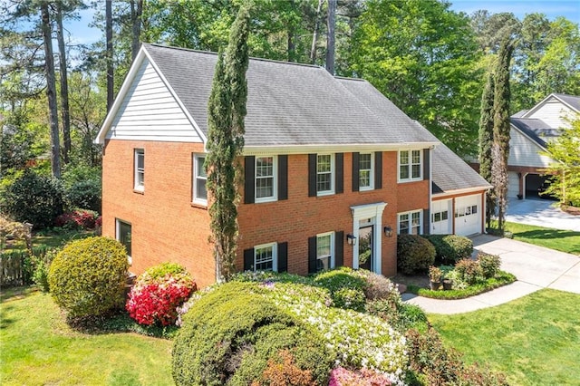 colonial inspired home with concrete driveway, a front lawn, brick siding, and an attached garage