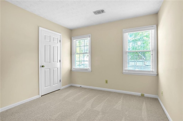 unfurnished room featuring baseboards, light carpet, and a textured ceiling