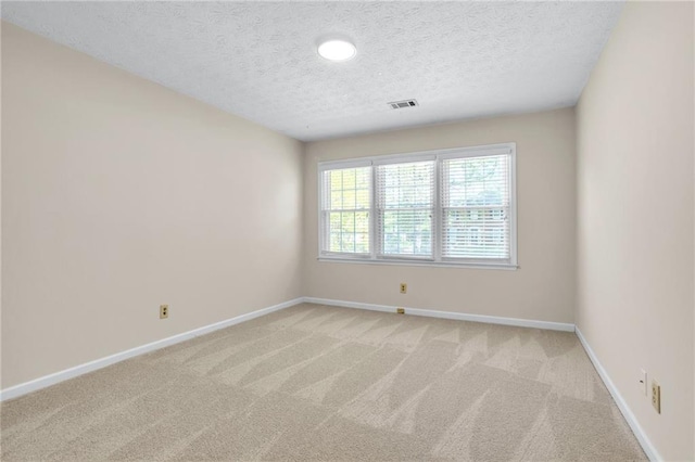 empty room featuring a textured ceiling, baseboards, and light carpet