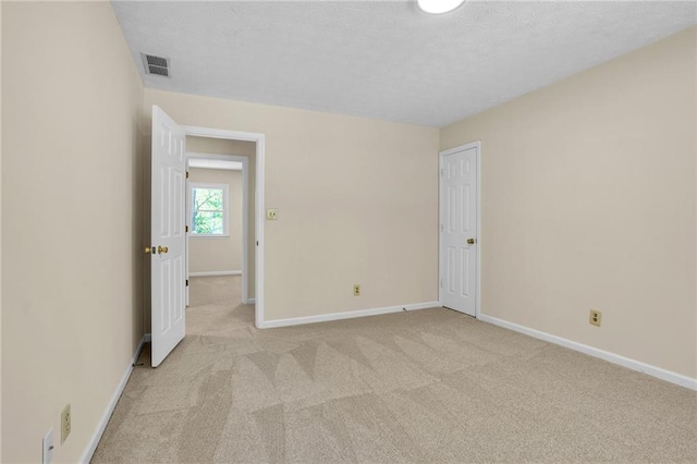 unfurnished room with light carpet, baseboards, and a textured ceiling