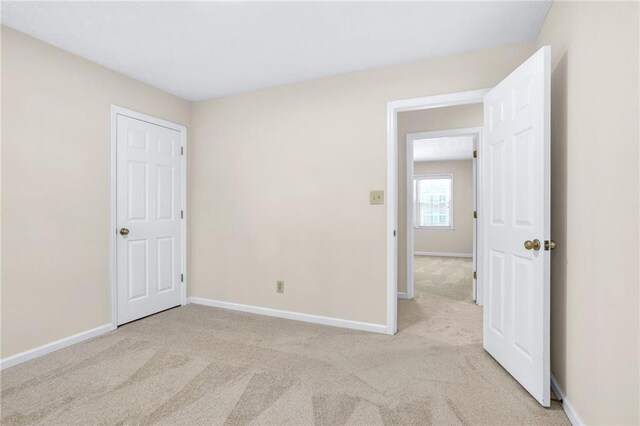 unfurnished bedroom with light carpet and baseboards