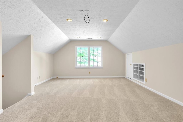 additional living space with a textured ceiling, carpet flooring, vaulted ceiling, and baseboards