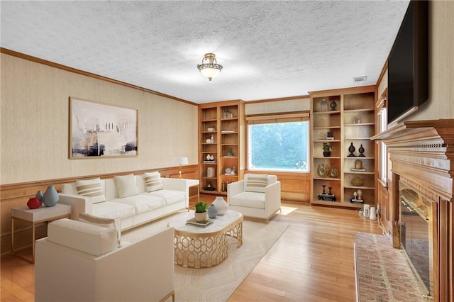 living area featuring crown molding, light wood-style floors, and a fireplace