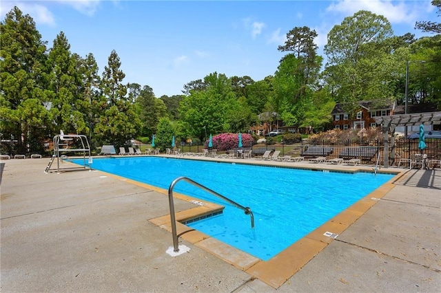 community pool featuring view of scattered trees and a patio area