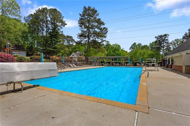 community pool featuring a patio area and view of wooded area