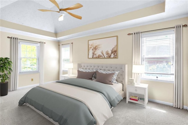carpeted bedroom with baseboards, a ceiling fan, vaulted ceiling, and a raised ceiling