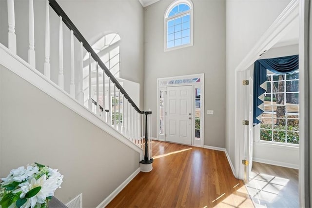 foyer entrance with hardwood / wood-style floors, a wealth of natural light, and a high ceiling