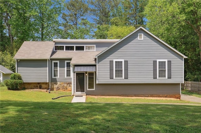view of front of home with fence, roof with shingles, and a front lawn