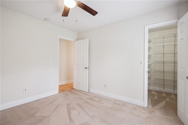 unfurnished bedroom featuring a closet, baseboards, carpet flooring, and a spacious closet