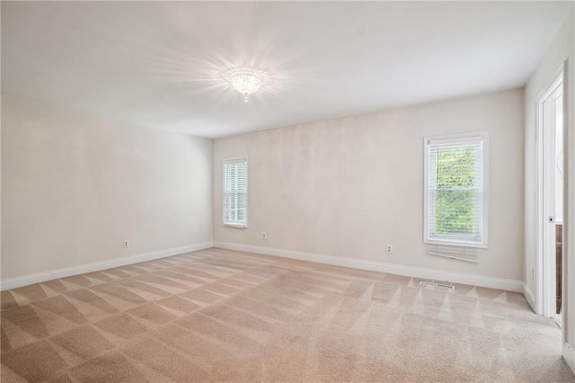 unfurnished room with baseboards, visible vents, and light carpet