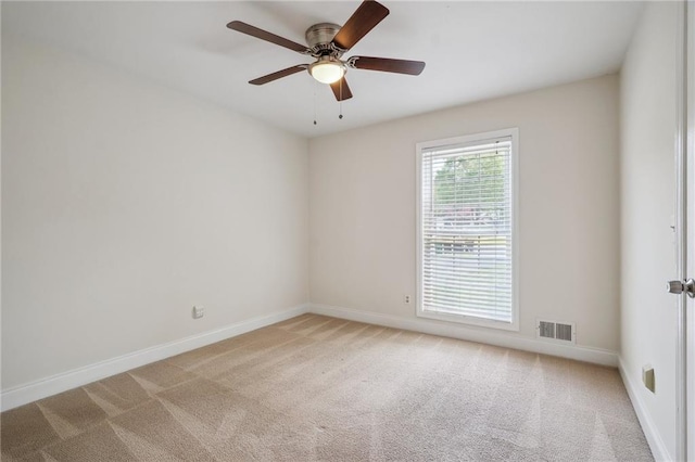 carpeted empty room featuring baseboards, visible vents, and ceiling fan