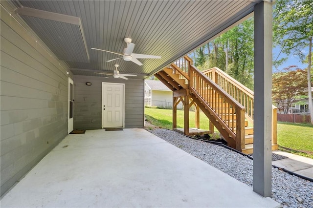 view of patio with fence, a ceiling fan, and stairway