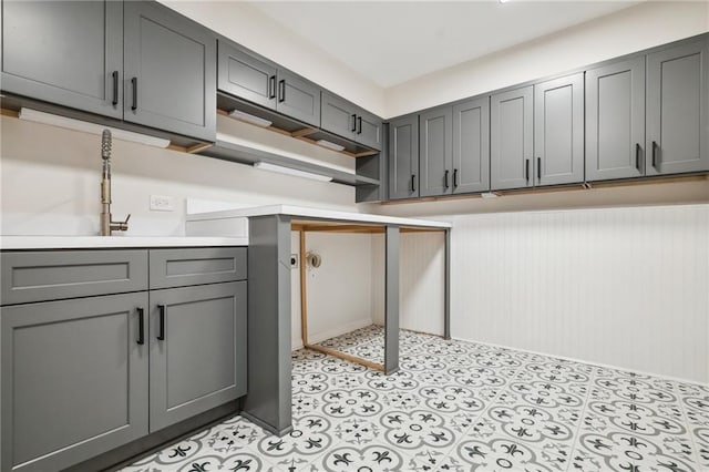 kitchen featuring open shelves, gray cabinets, and light countertops