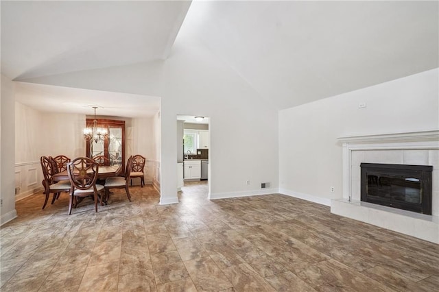 living area with baseboards, a fireplace, a notable chandelier, and high vaulted ceiling