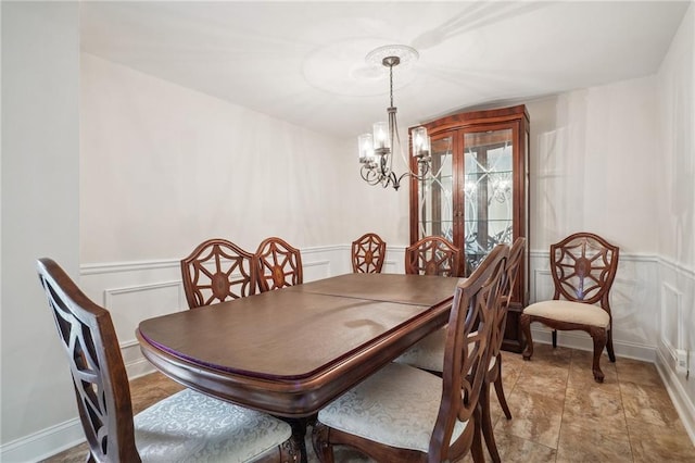 dining space featuring a notable chandelier, wainscoting, and a decorative wall